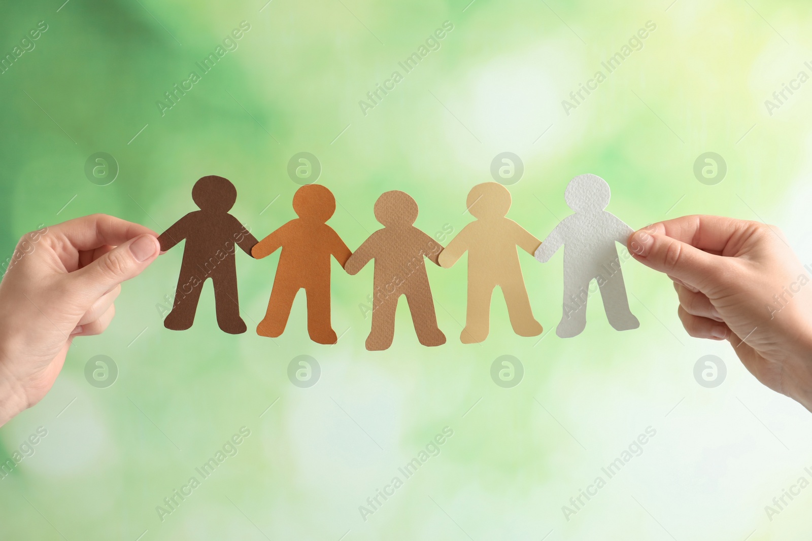 Photo of Young woman holding paper people on blurred background. Unity concept