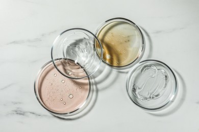 Photo of Petri dishes with liquids on white marble table, flat lay