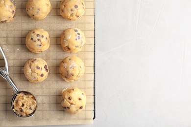 Photo of Raw cookie dough with chocolate chips and scoop on parchment paper, top view