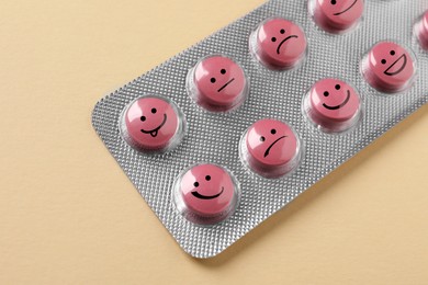 Pink pills with different emotional faces in blister on beige background