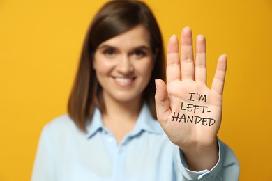 Left-handed woman against yellow background, focus on palm with text 