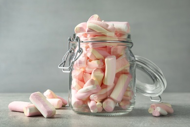 Glass jar with tasty marshmallows on light grey table, closeup