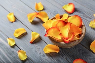 Photo of Bowl with rose petals on wooden background. Space for text