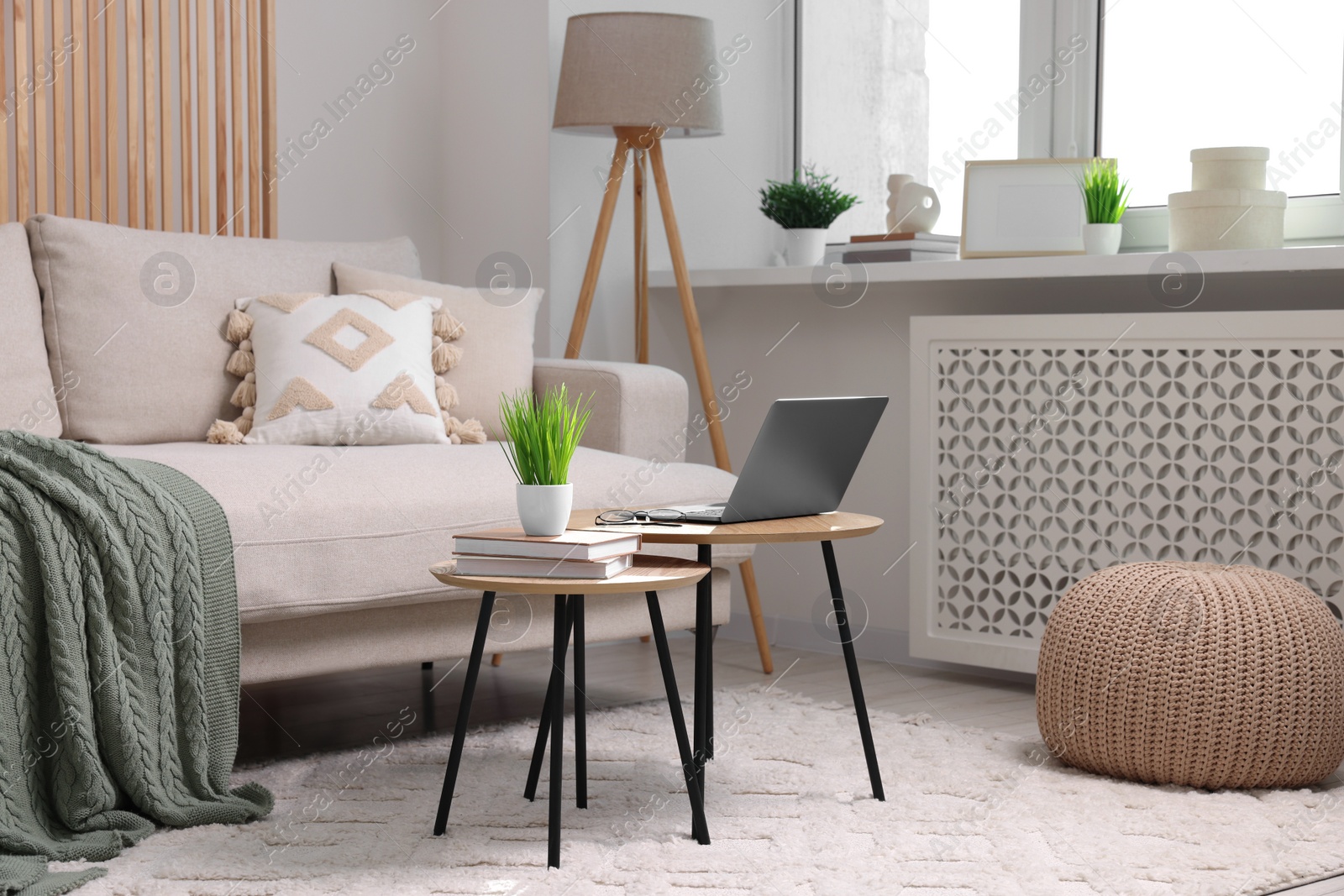 Photo of Potted artificial plant, laptop and books on wooden nesting tables indoors