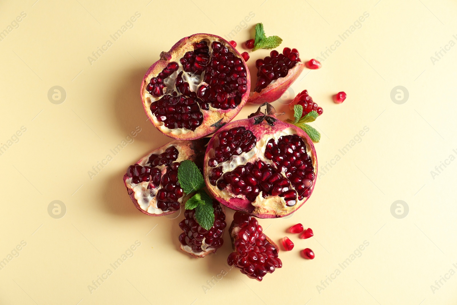 Photo of Ripe pomegranates and seeds on color background, flat lay