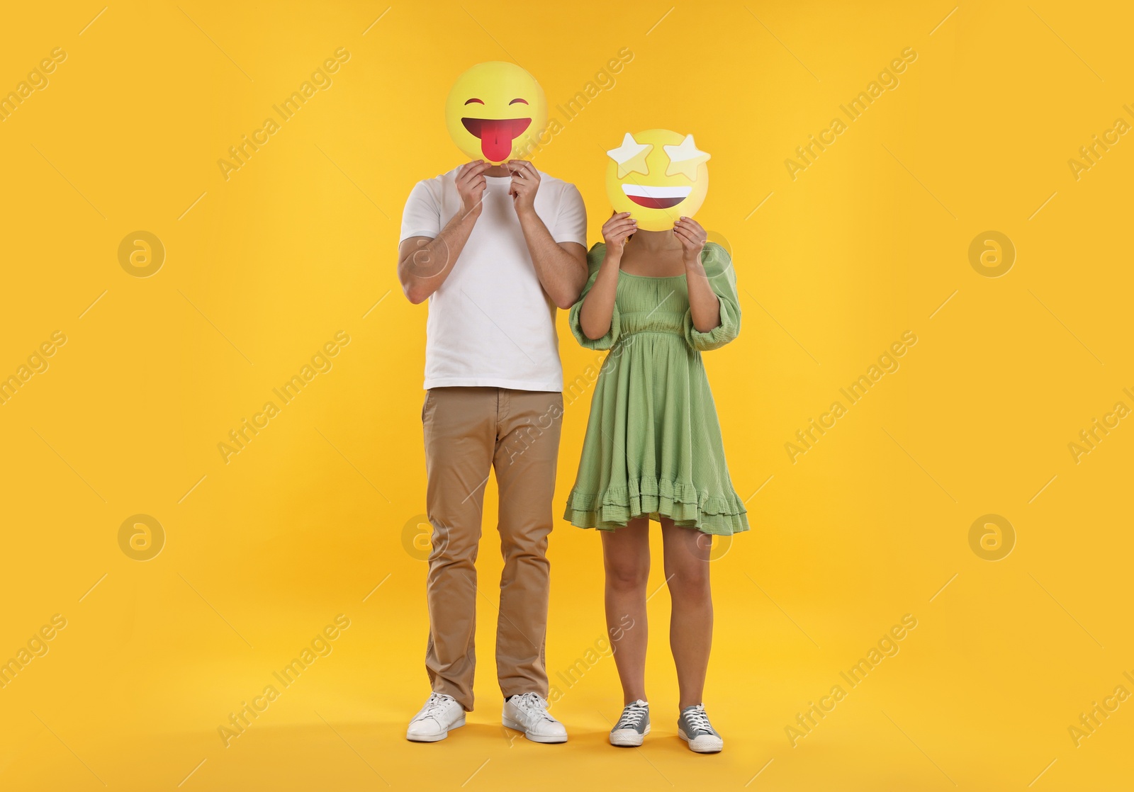 Photo of People covering faces with emoticons on yellow background