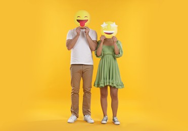 People covering faces with emoticons on yellow background