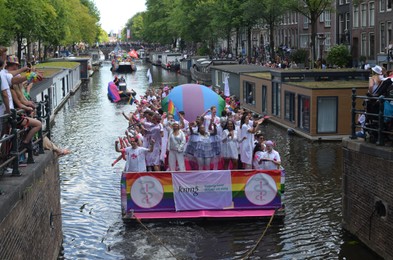 Photo of AMSTERDAM, NETHERLANDS - AUGUST 06, 2022: Many people in boats at LGBT pride parade on river