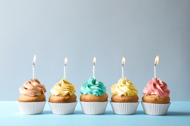 Photo of Delicious birthday cupcakes with candles on light background