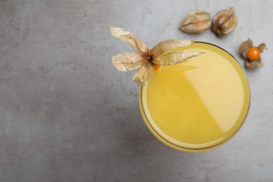 Photo of Tasty cocktail decorated with physalis fruit on grey table, flat lay. Space for text