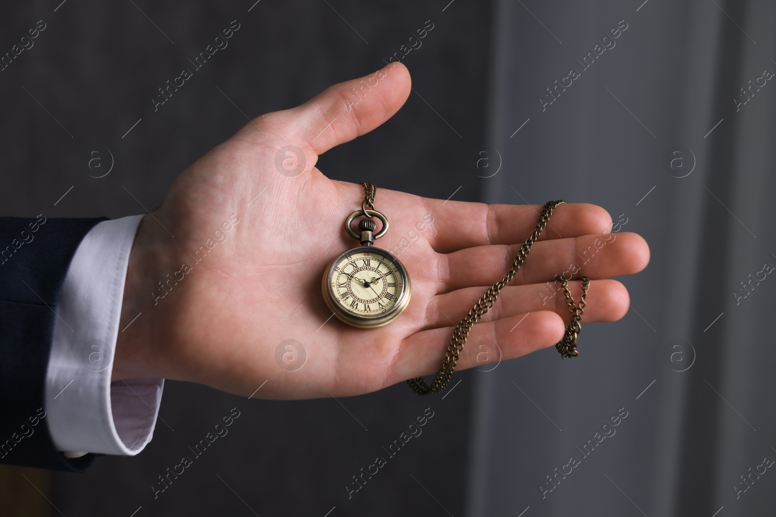 Photo of Man holding chain with elegant pocket watch on blurred background, closeup