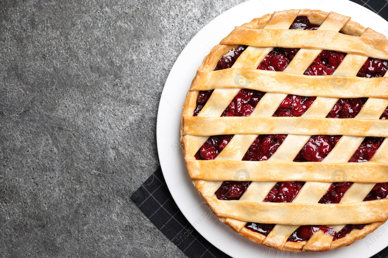 Photo of Delicious fresh cherry pie on grey table, top view. Space for text