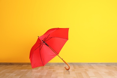 Photo of Beautiful open umbrella on floor near color wall with space for design