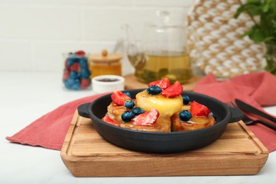 Photo of Delicious cottage cheese pancakes with fresh berries and honey served on white table