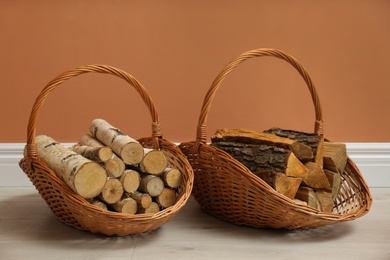 Photo of Wicker baskets with firewood near brown wall indoors