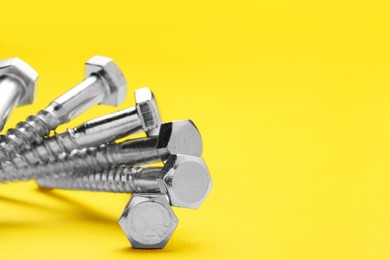 Photo of Many self-tapping screws on yellow background, closeup. Space for text