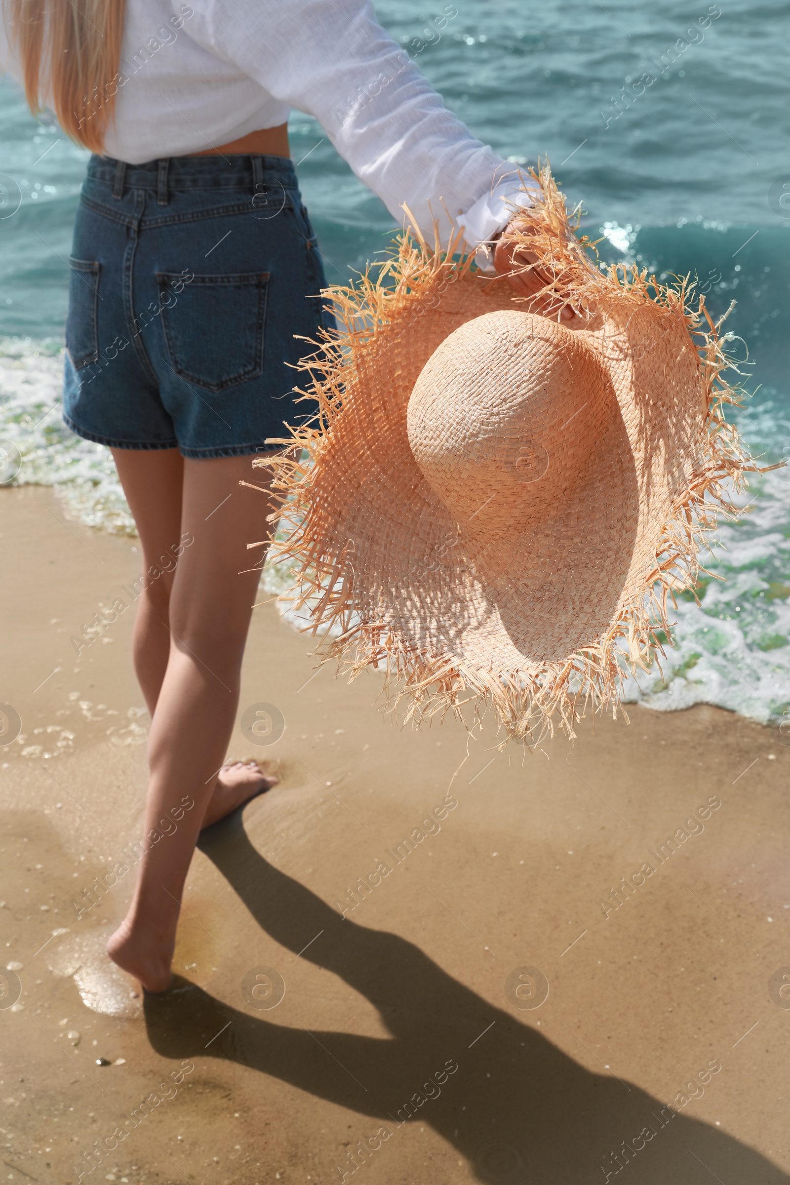 Photo of Young woman with straw hat near sea on sunny day in summer, closeup