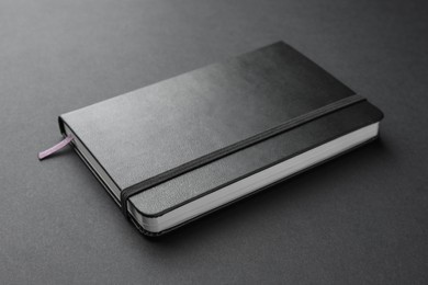 Photo of Closed notebook with blank cover on black background