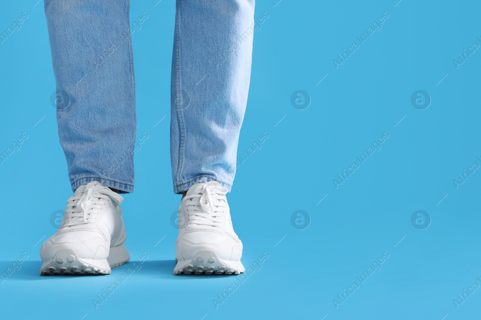 Photo of Man wearing stylish sneakers on light blue background, closeup. Space for text
