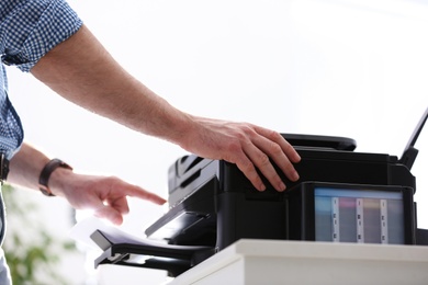 Photo of Employee using modern printer in office, closeup