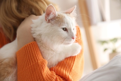 Photo of Woman with cute fluffy cat indoors, closeup