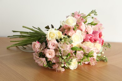 Beautiful bouquet of fresh flowers on wooden table near white wall