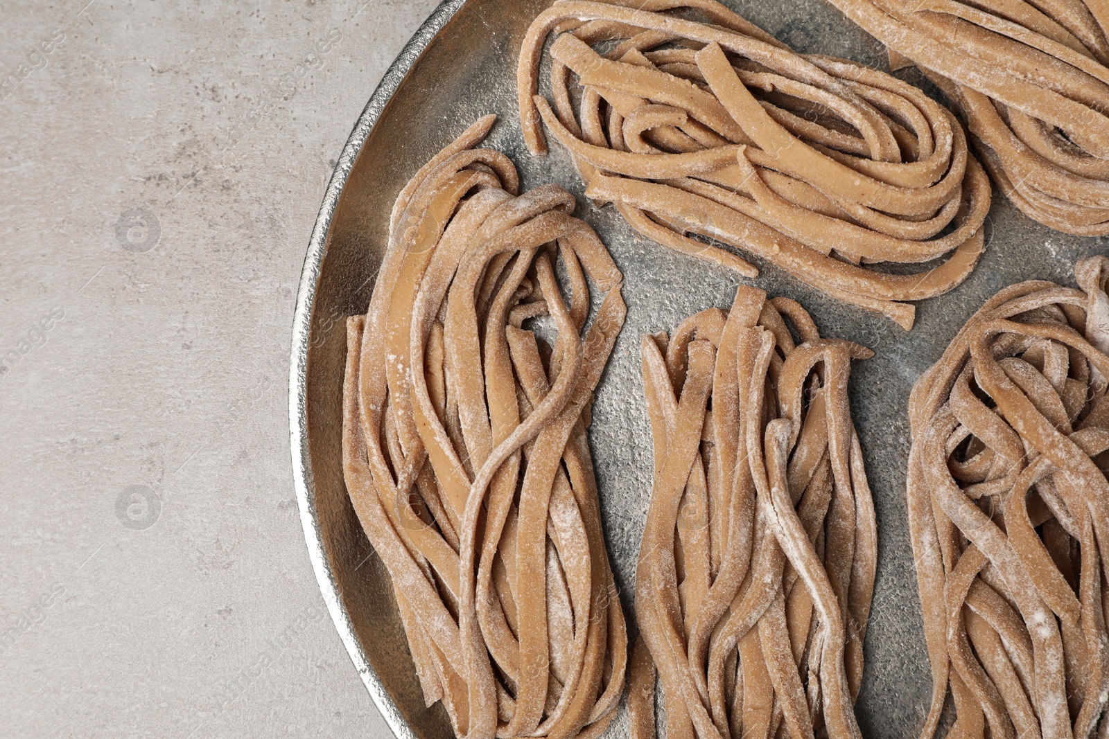 Photo of Uncooked homemade soba with tray on light table, top view