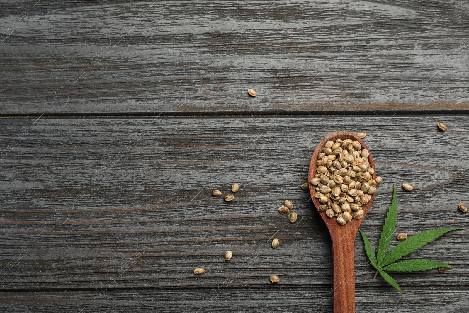 Photo of Organic hemp seeds and leaf on dark wooden table, flat lay. Space for text