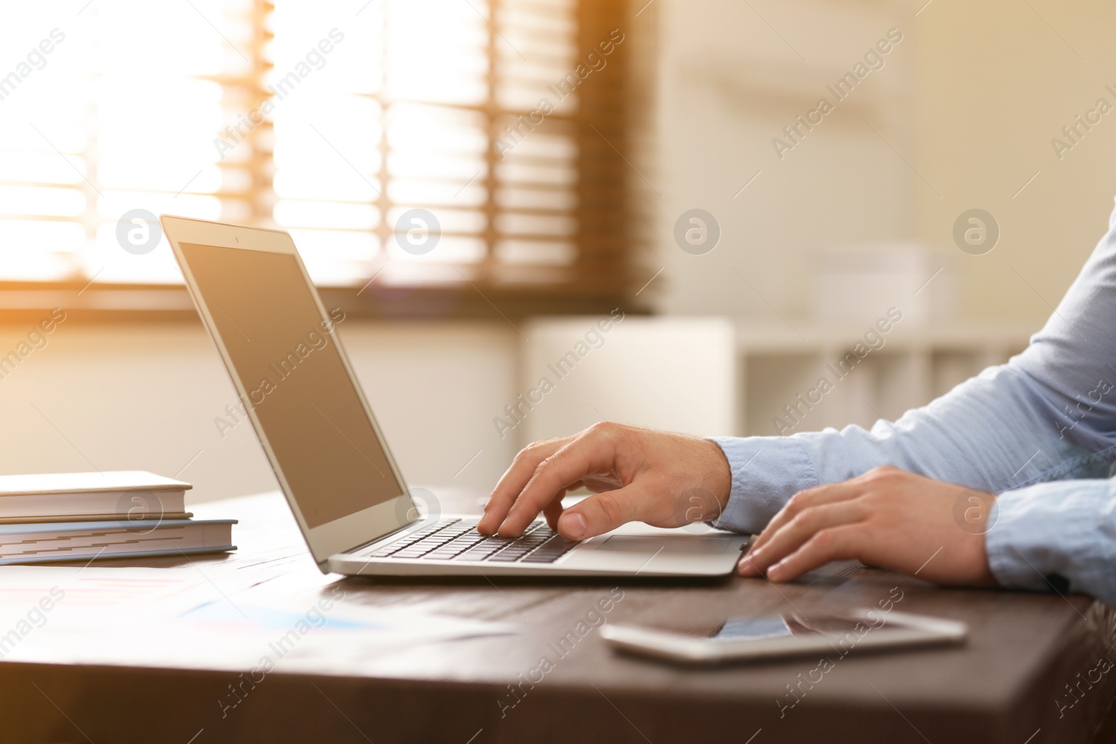 Image of Man working with laptop at table in office, closeup