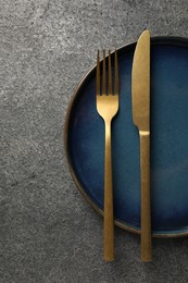 Photo of Stylish golden cutlery and plate on grey table, top view