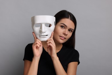 Photo of Multiple personality concept. Woman with mask on grey background