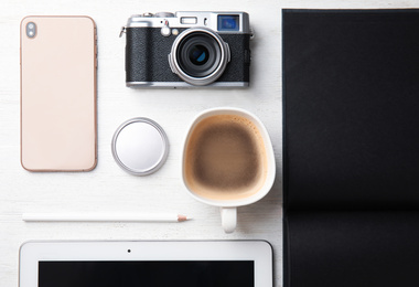 Photo of Flat lay composition with vintage camera and smartphone on white wooden table. Designer's workplace