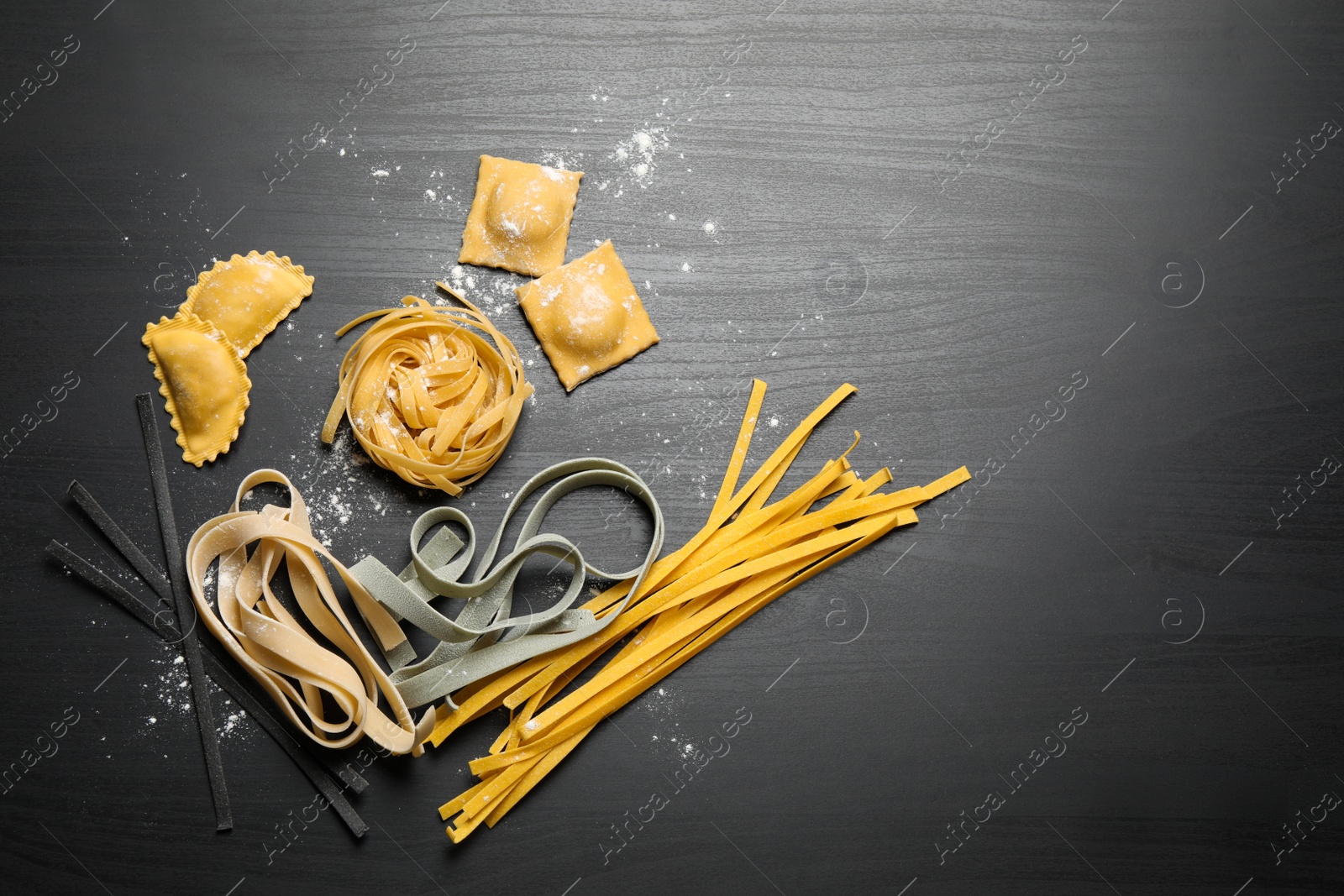 Photo of Flat lay composition with different types of pasta on black wooden table