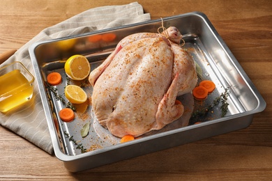 Baking dish with raw spiced turkey on wooden background