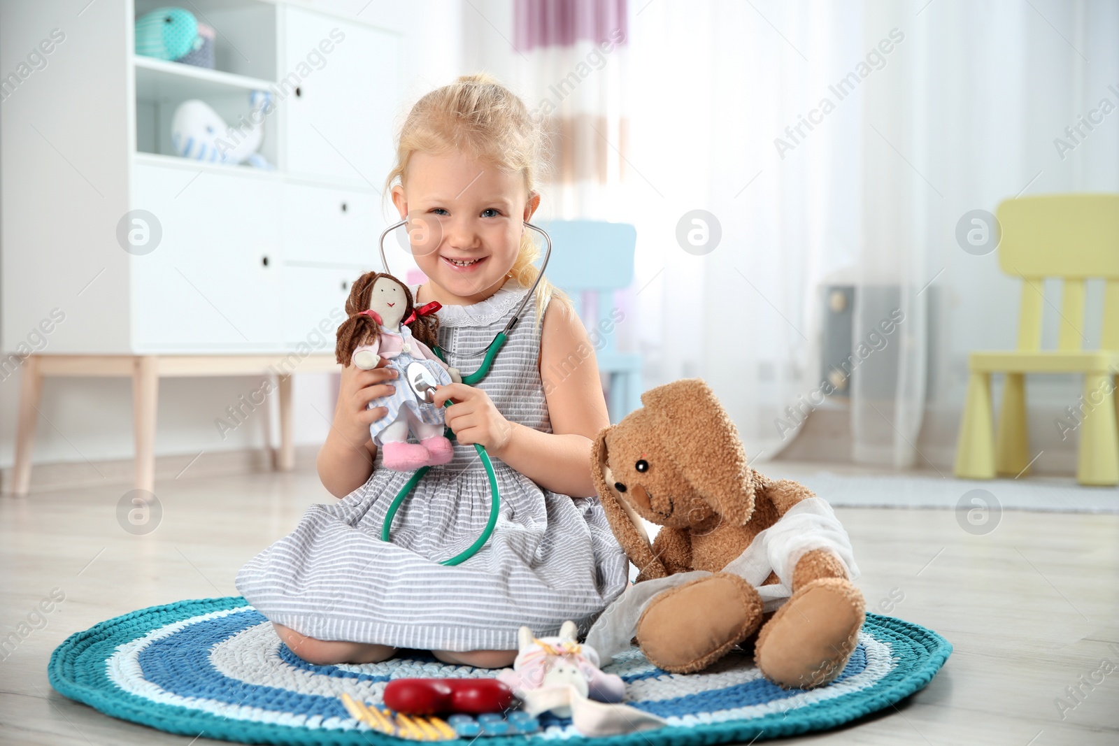 Photo of Cute child imagining herself as doctor while playing with stethoscope and toy at home