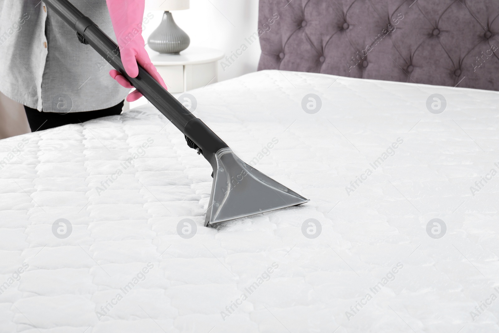 Photo of Woman disinfecting mattress with vacuum cleaner, closeup. Space for text