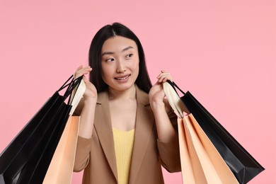 Smiling woman with shopping bags on pink background