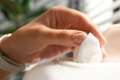 Photo of Woman taking wet wipe from pack on blurred background, closeup