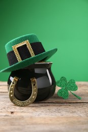 Photo of St. Patrick's day. Pot of gold with leprechaun hat, horseshoe and decorative clover leaf on wooden table