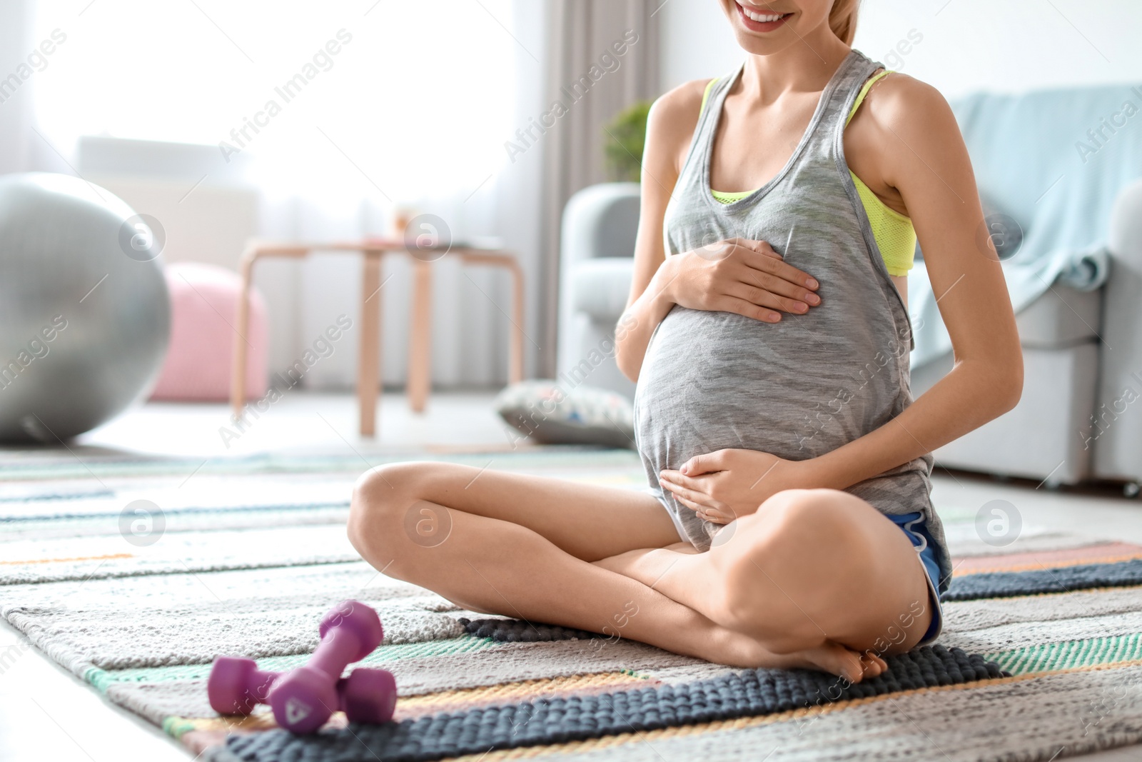 Photo of Young pregnant woman doing exercises at home