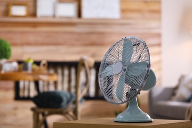 Photo of Modern electric fan on wooden table indoors. Space for text