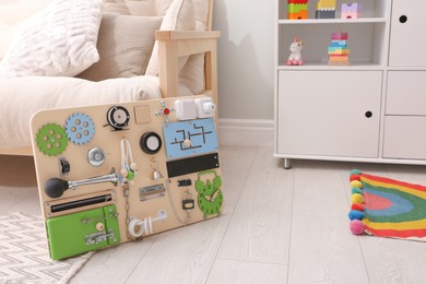 Photo of Busy board on floor indoors, space for text. Baby sensory toy