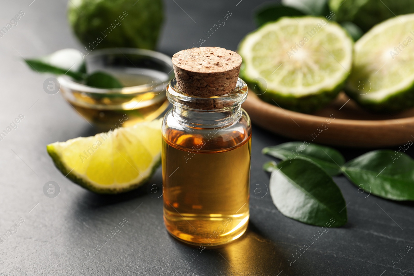 Photo of Bottle of bergamot essential oil on dark table, closeup