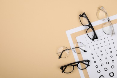 Photo of Vision test chart and glasses on beige background, flat lay. Space for text