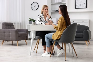 Psychologist working with teenage girl at table in office