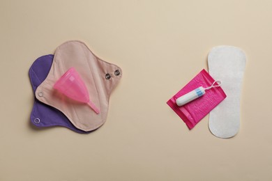 Photo of Reusable and disposable menstrual hygiene products on beige background, flat lay