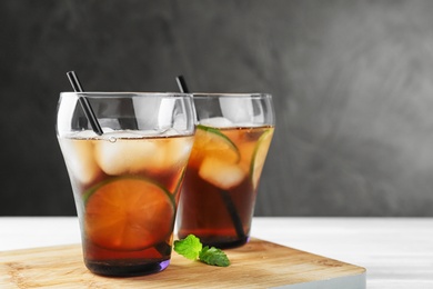 Photo of Glasses of refreshing iced tea on white table against grey background