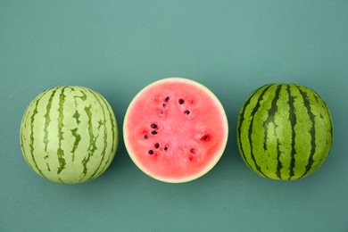 Cut and whole ripe watermelons on teal background, flat lay