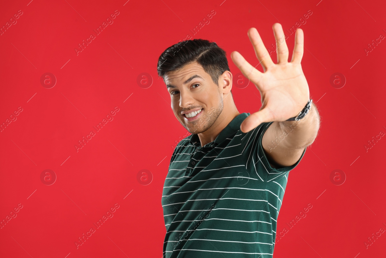 Photo of Man showing number five with his hand on red background