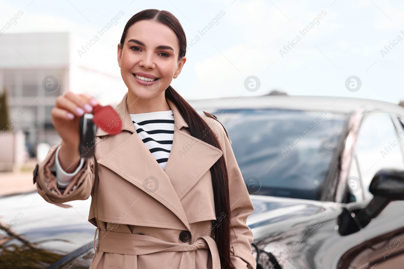 Photo of Woman holding car flip key near her vehicle outdoors